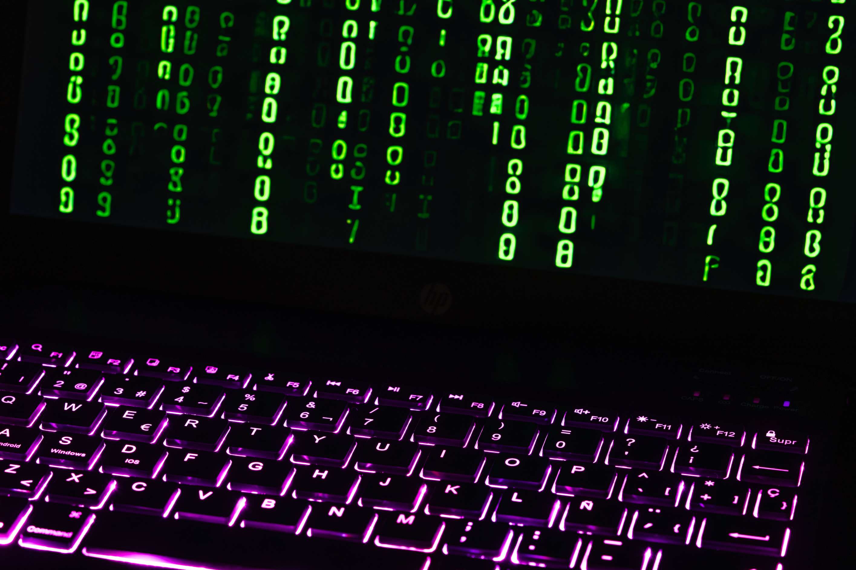 Close view of code on a monitor in a dim office with illuminated keyboard